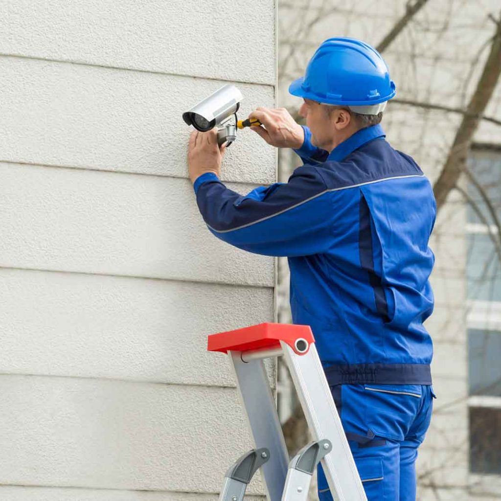 male technician standing on stepladder fitting cctv camera 1.jpg